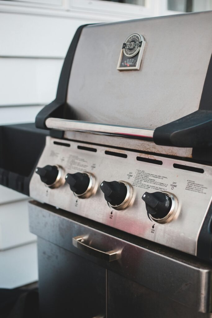 Close-up of a stainless steel gas grill with four control knobs, perfect for outdoor cooking.